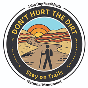 The images says Don't Hurt the Dirt Stay on Trails with a person hiking on the trails at Painted Hills