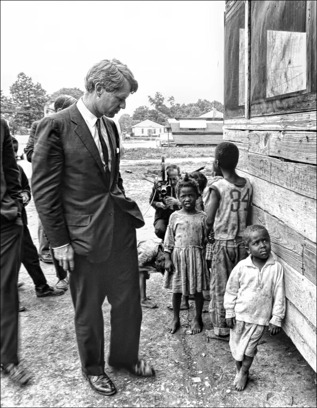 RFK on the left observing children near a building