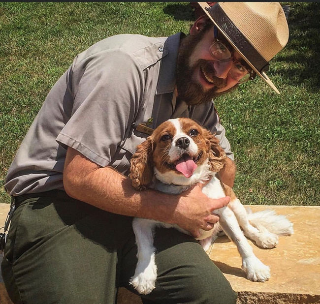 A park ranger sitting with a dog.