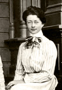 Photo of Helen Muir Funk. Young woman with glasses, sitting in a dress.