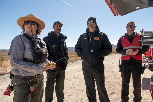 A group of four people including a park ranger and county fire staff chat.