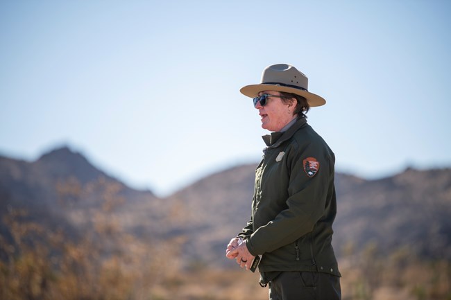 A uniformed park ranger speaks outside.