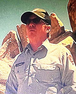 A uniformed park ranger in a ball cap.