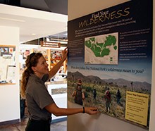 park ranger installing new wilderness exhibit on the visitor center wall