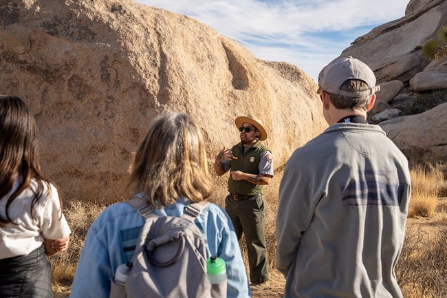 A park ranger speaks to a crowd of visitors on a trail.