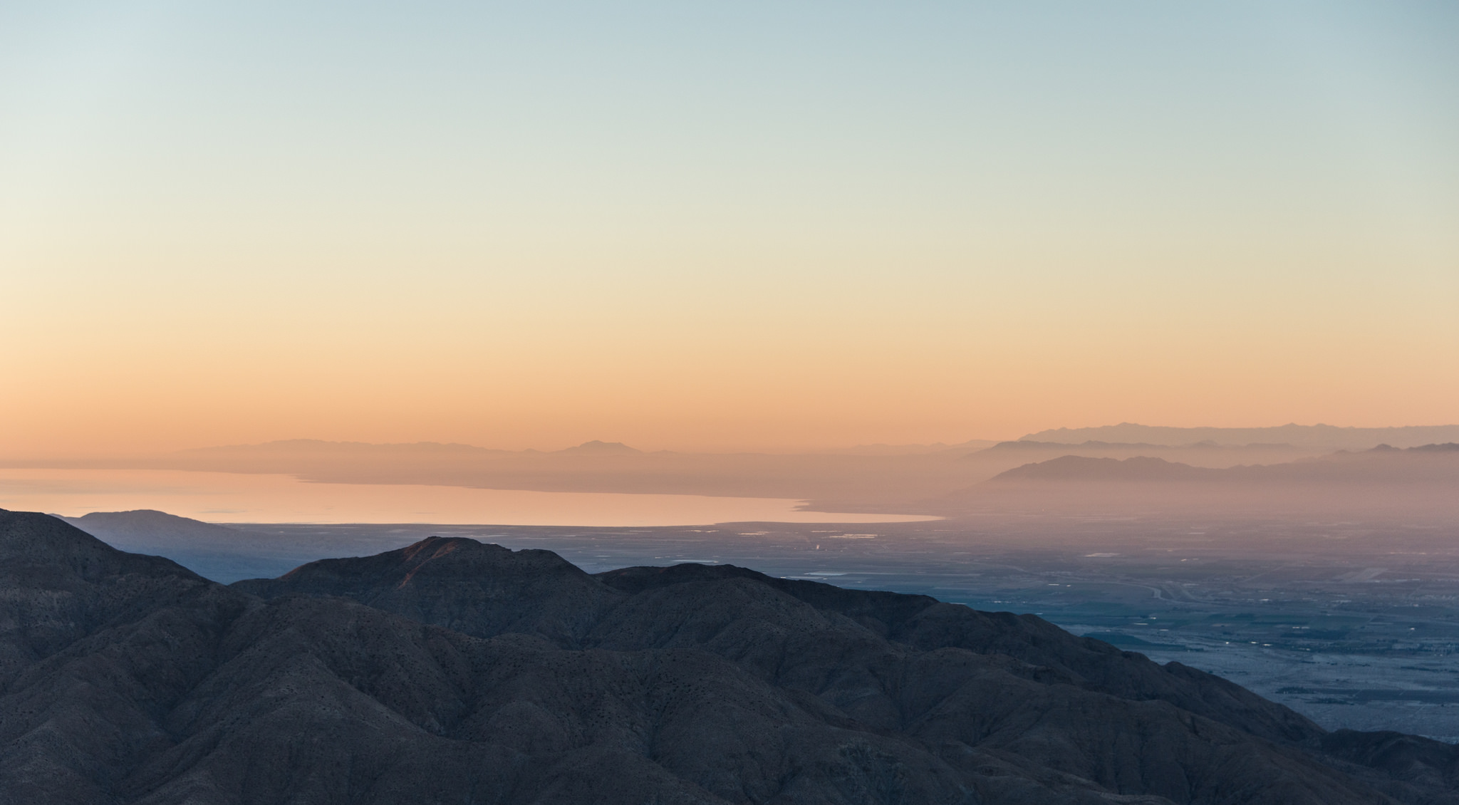 Looking out over the Salton Sea from Keys View. It is just after sunset and the light is very pink. The foreground mountains are blue.