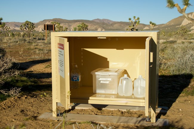 Water and food containers stored in tan metal bin