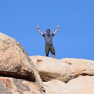 A man standing on top of rocks with his arms stretched up into the air.