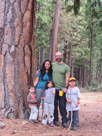 Two adults and three children standing in a forest.