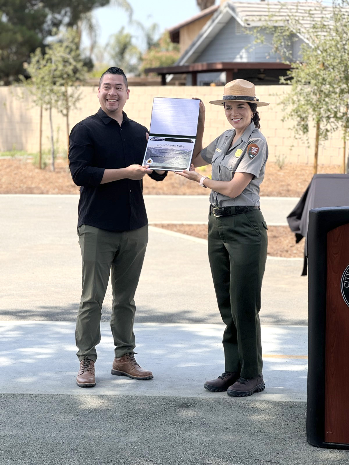 A woman in National Park Service uniform and a man hold a certificate