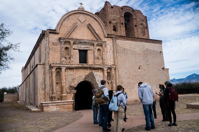 A group of students gather outside of an 18th century mission