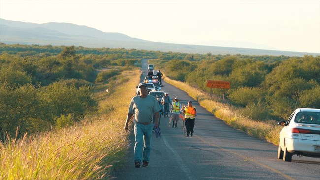 Pilgrims travel along a road on their way to Magdalena in Sonora as a car passes by.