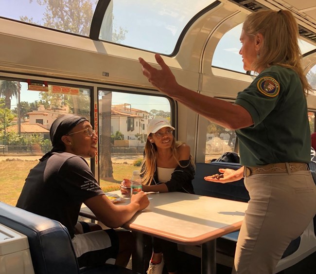 A woman talks to a couple on a train