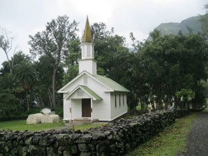 A small white church building enclosed by a low rock wall.