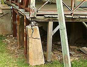 A corner cement foundation block of a building with a large crack.