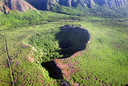 An aerial view of a crater below cliffs.