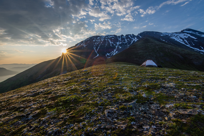 Sunrise over campsite and rugged mountains