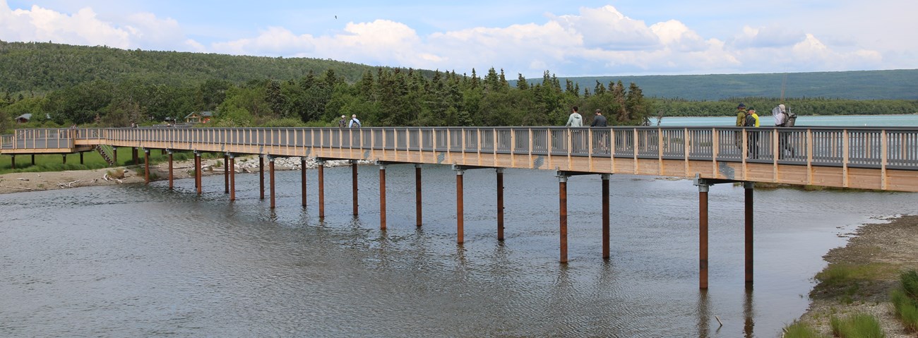 visitors cross elevated bridge over a river
