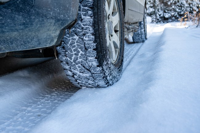 A vehicle drives on snowy roads in the wintertime.