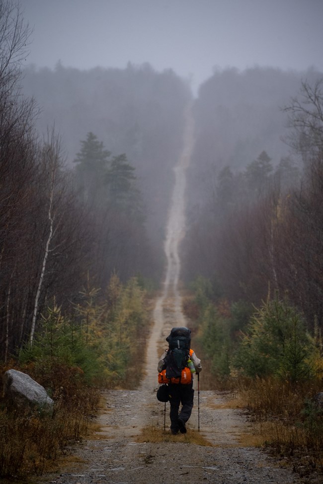 A backpacker travels along the International Appalachian Trail and into the fog.