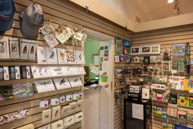 Displays of pins, hats, books, and other souvenirs on the walls next to an information desk.