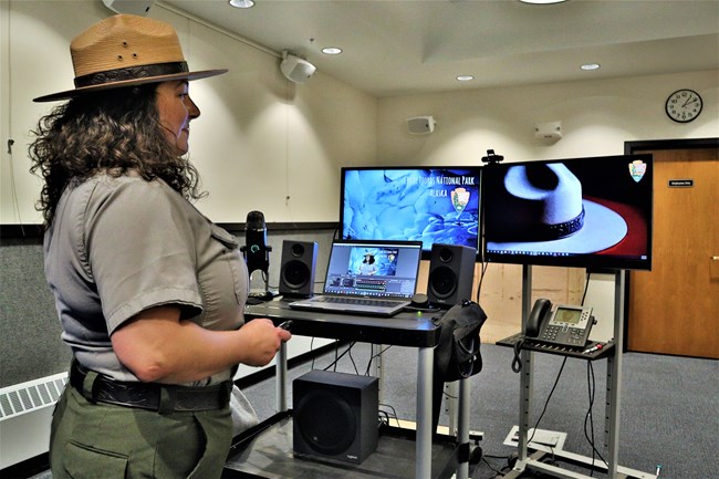 A park ranger standing in front of two computer screens