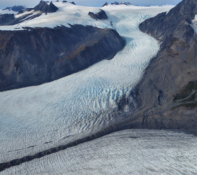 A brown line of sediment from a mountain sits between two glaciers