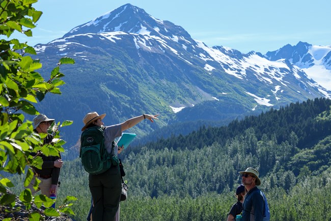 Ranger with groups points with mountains behind