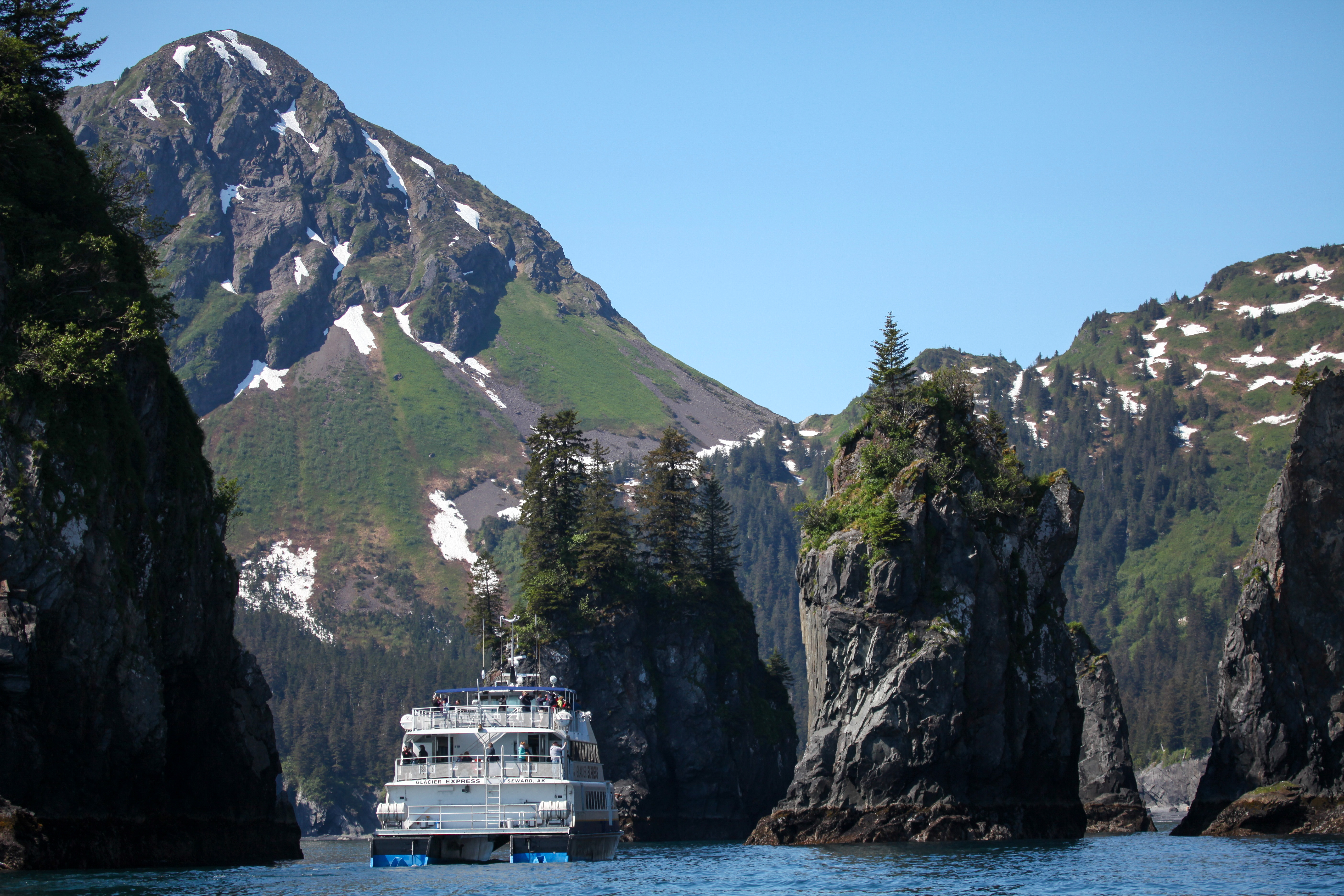 A large boat approaches coastal sea stacks