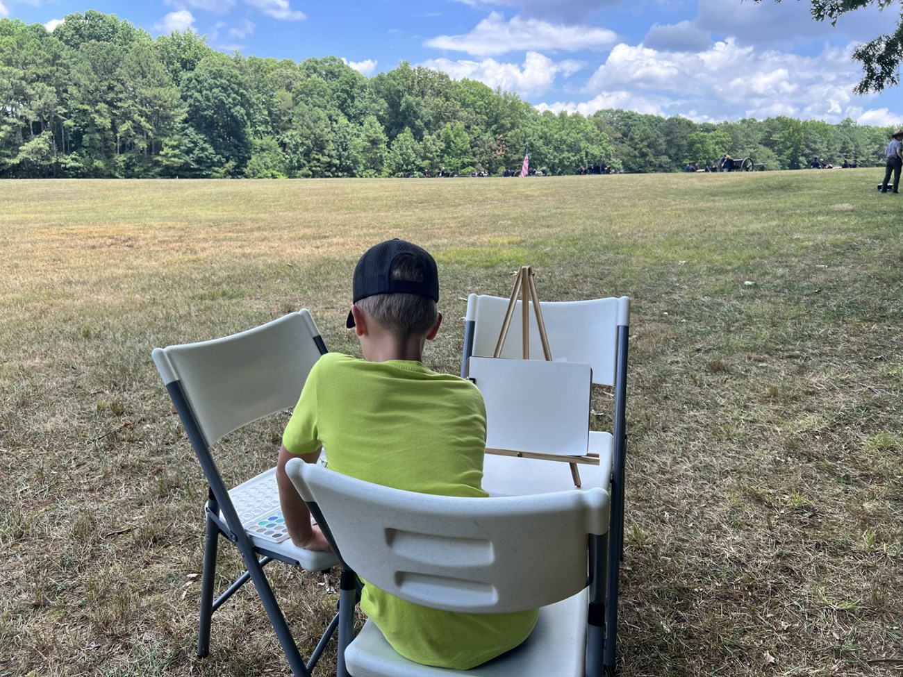 Child sits in field painting.