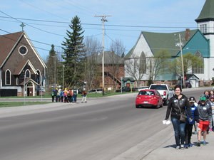 Groups of students follow chaperone leaders along a street.