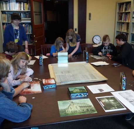 Emily Riippa, an archivist at the Michigan Technological University Archives and Copper Country Historical Collections in Houghton is seen here with fourth grade students participating in the primary sources station in the LSCMC archives reading room.