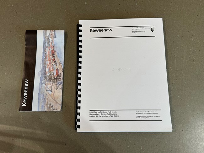 A copy of the Keweenaw National Historical Park's unigrid brochure and the braille copy of the publication.