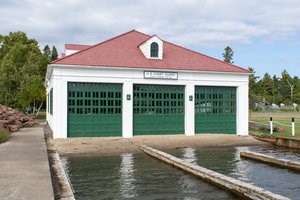 Exterior building with white siding and large green doors that is part o the Eagle Harbor Lifesaving Station complex.