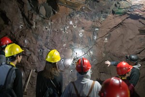 A group of visitors with hardhats explores the underground of the Quincy.