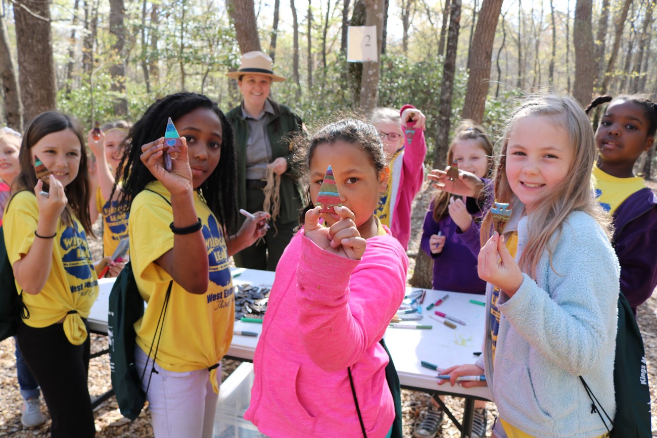 9 students and a park ranger are working on painting arrowheads with their own personal designs.