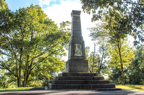 A stone monument is surrounded by trees.