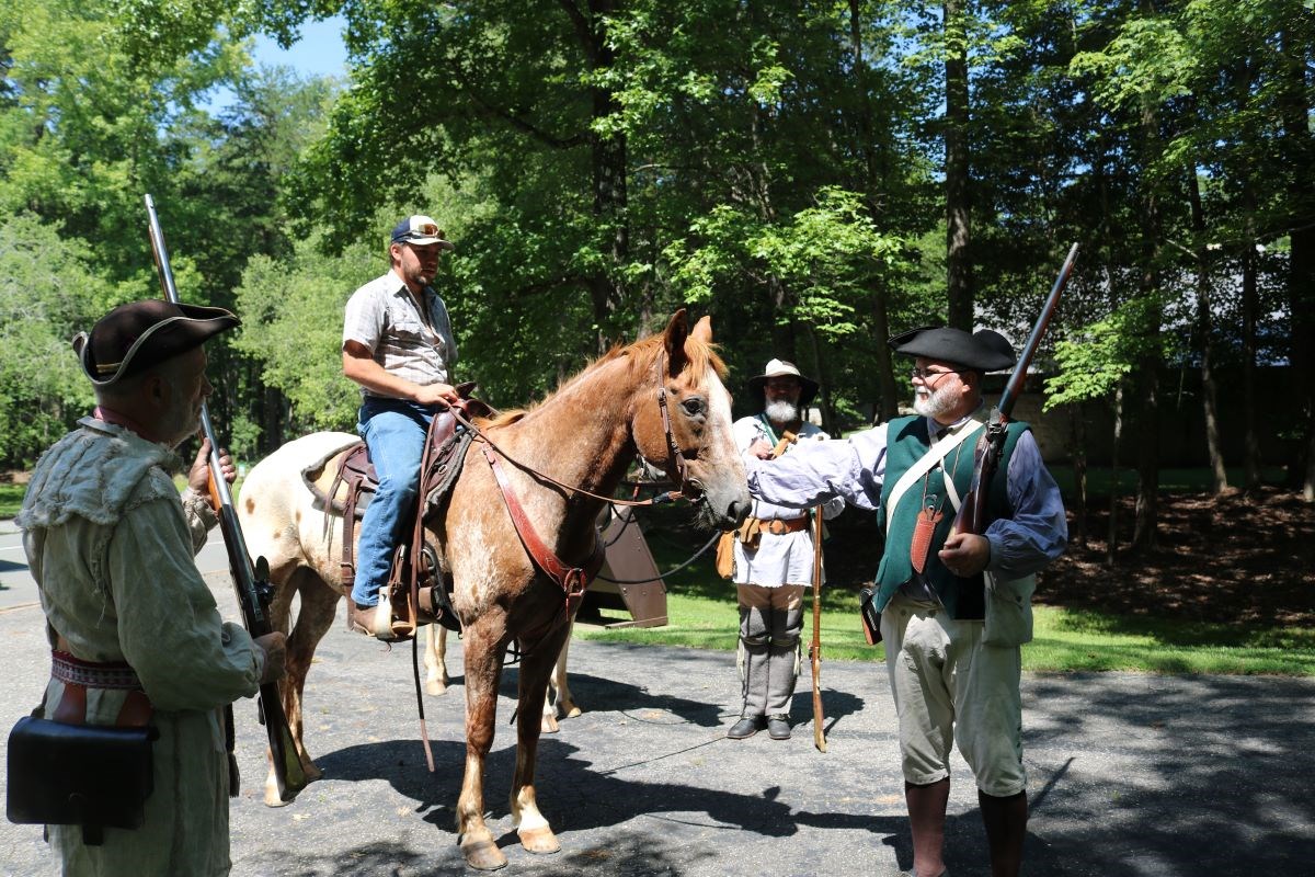 A man sits on a horse with two men in soldier gear around him.