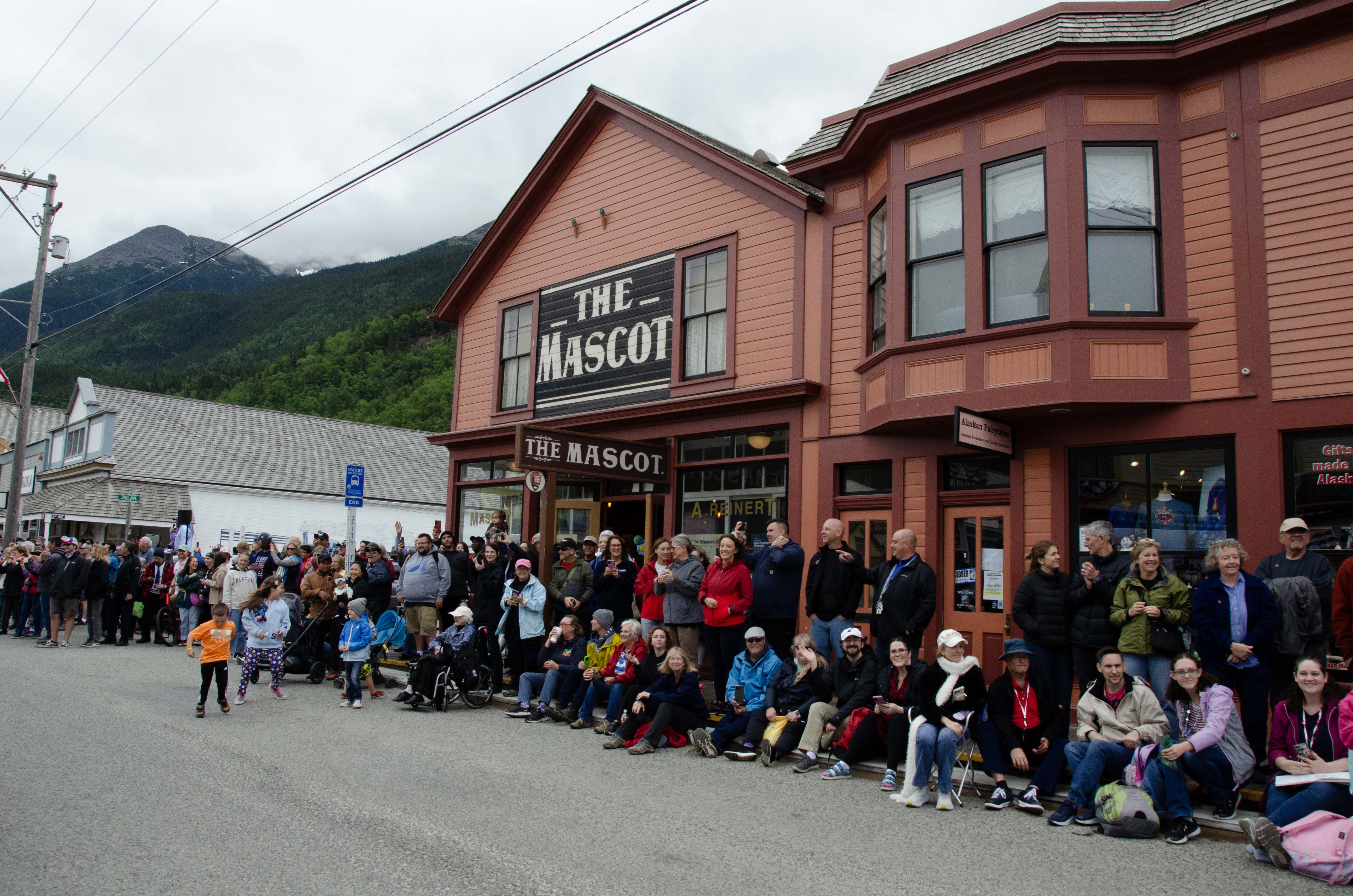 Fourth of July crowds sit outside the Mascot. A burnt orange building that is restored to the  late 1890s atmosphere.