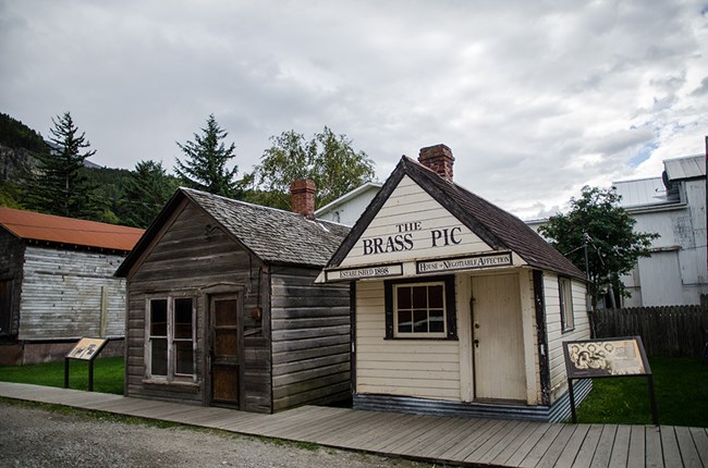 two small buildings with wayside exhibits on either side