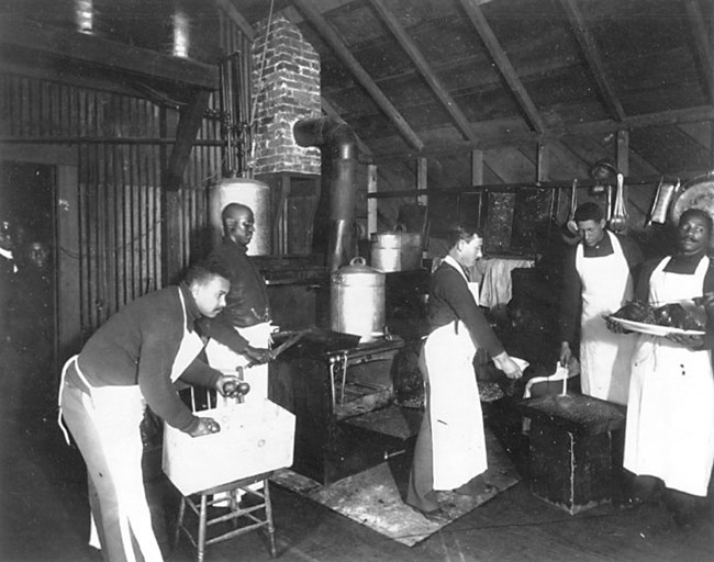 Historic photo of five men in aprons in a kitchen