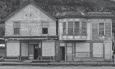 Black and white photo of three unkempt old buildings.