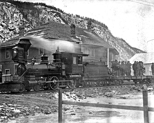 Steam engine in front of a large building in the winter
