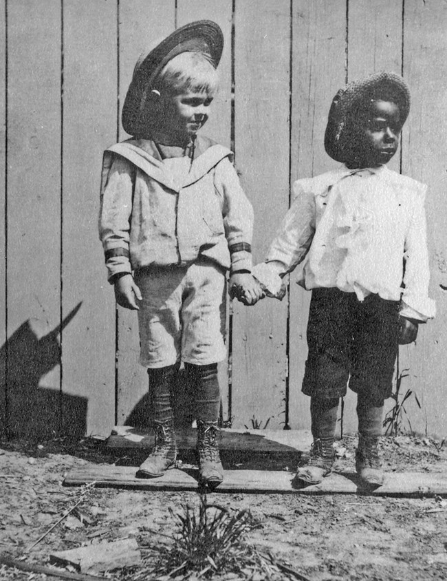 Two little boys in hats hold hands