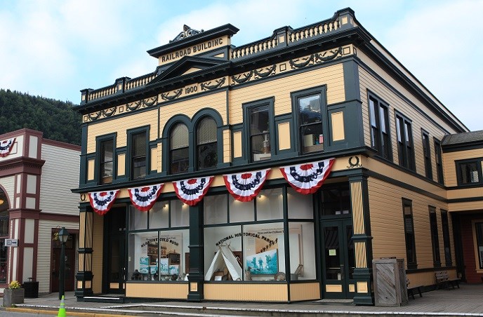 Historic yellow building with green trim decorated with patriotic bunting.