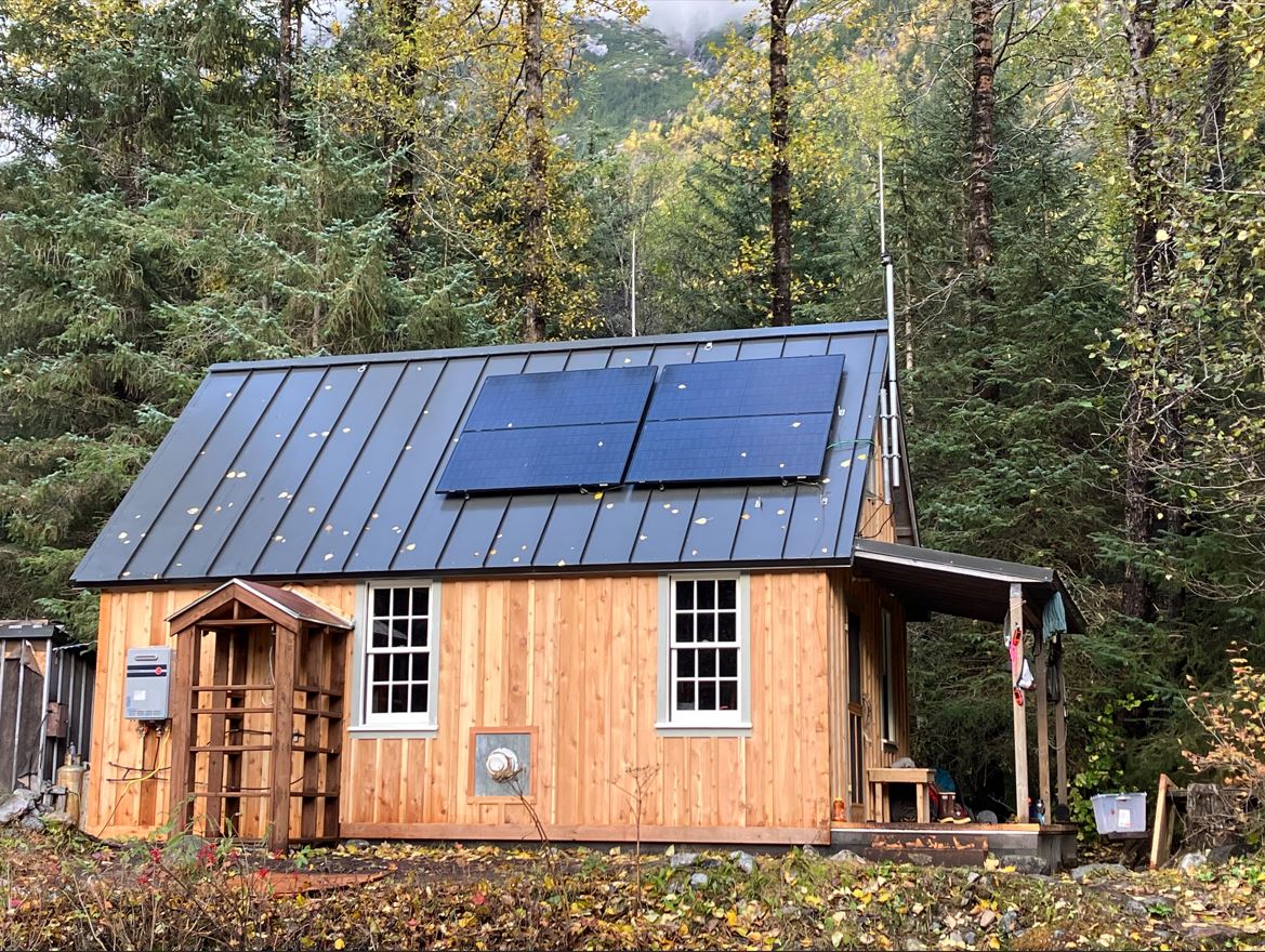 Wooden cabin surrounded by trees in a forest clearing.