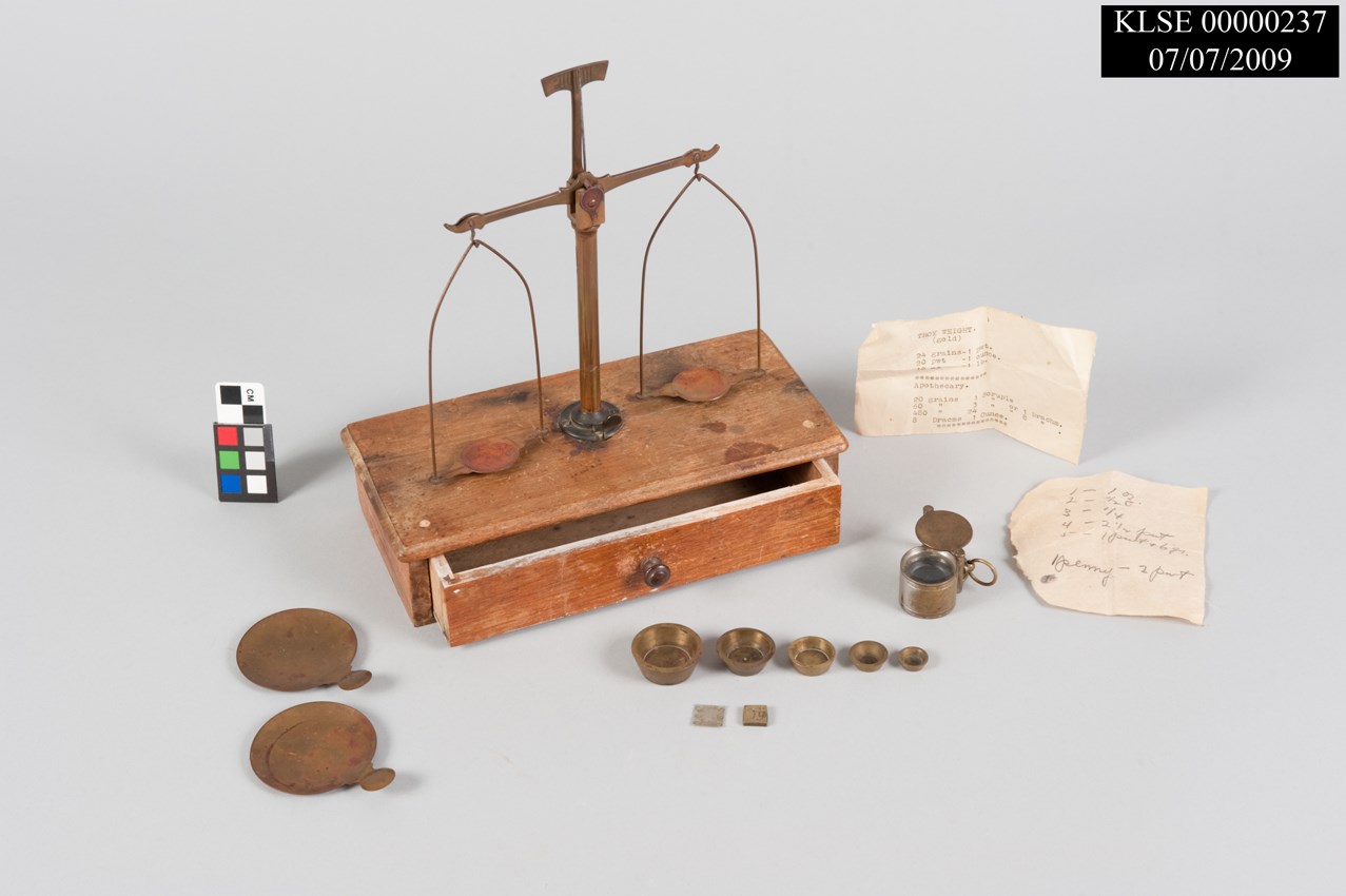 Artifact photo showing gold scales, metal pieces, paper labels, and color card with text "KLSE 0000237 07/07/2009"