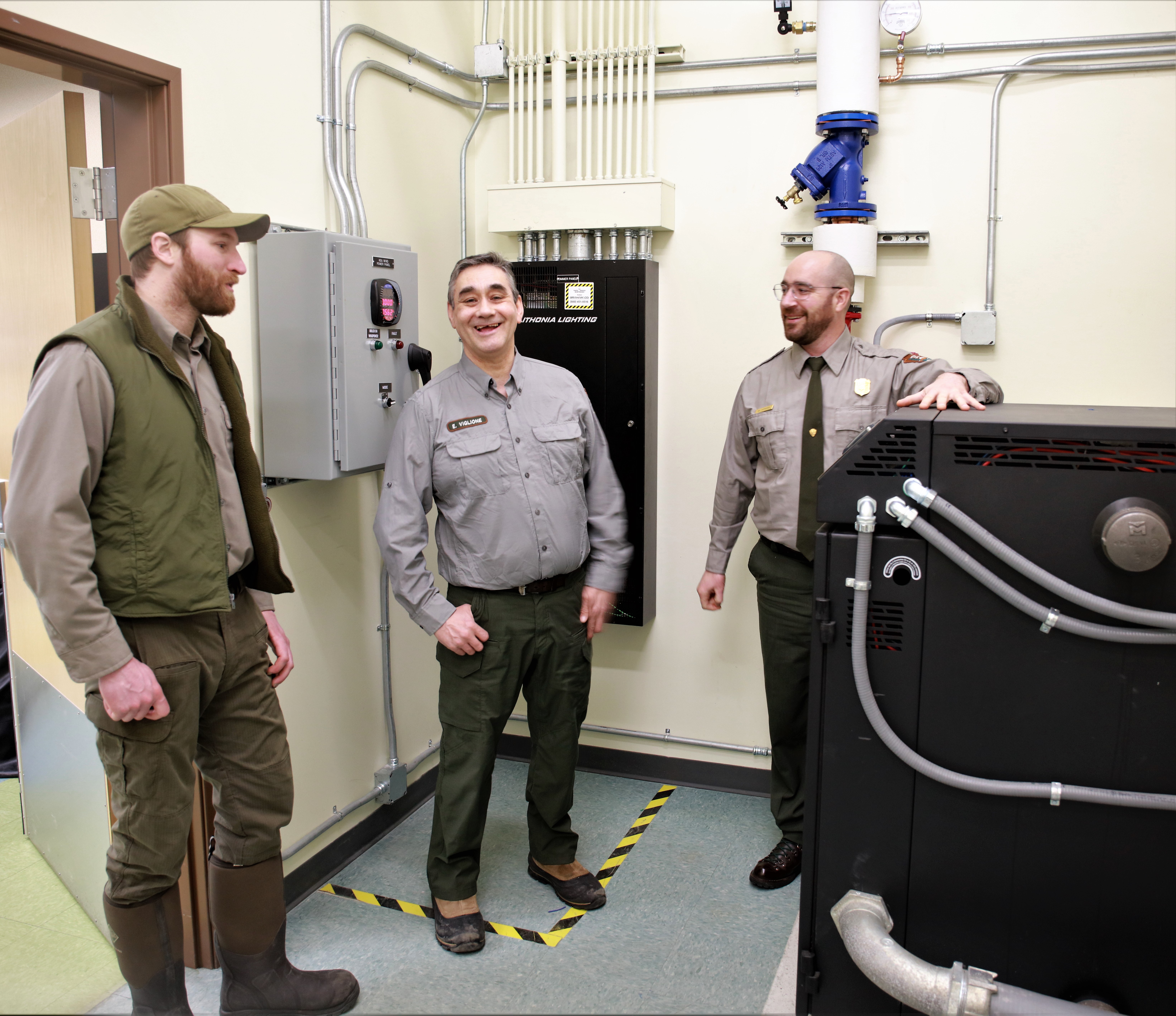 NPS employees stand in front of the new boiler powered by wind energy.