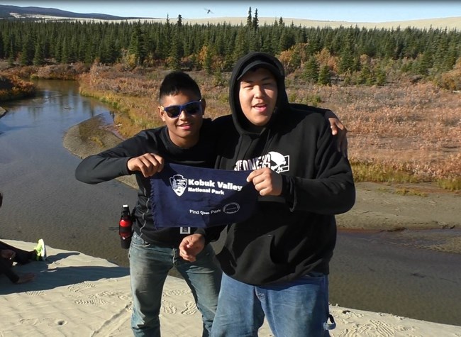 Two visitors hold up a Kobuk Valley National Park sign