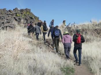A group of visitor's hikes uphill through Captain Jack's Stronghold